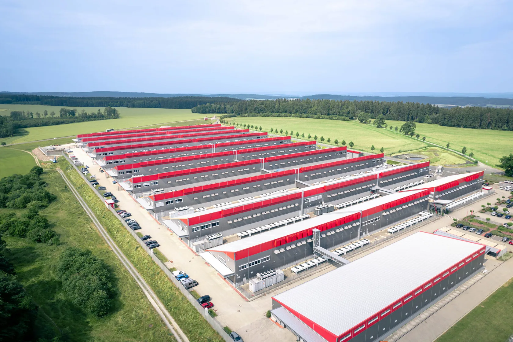 Rechenzentrum von Hetzner in Deutschland, aus der Luft: Reihen rot gedeckter Hallen in offener Landschaft
